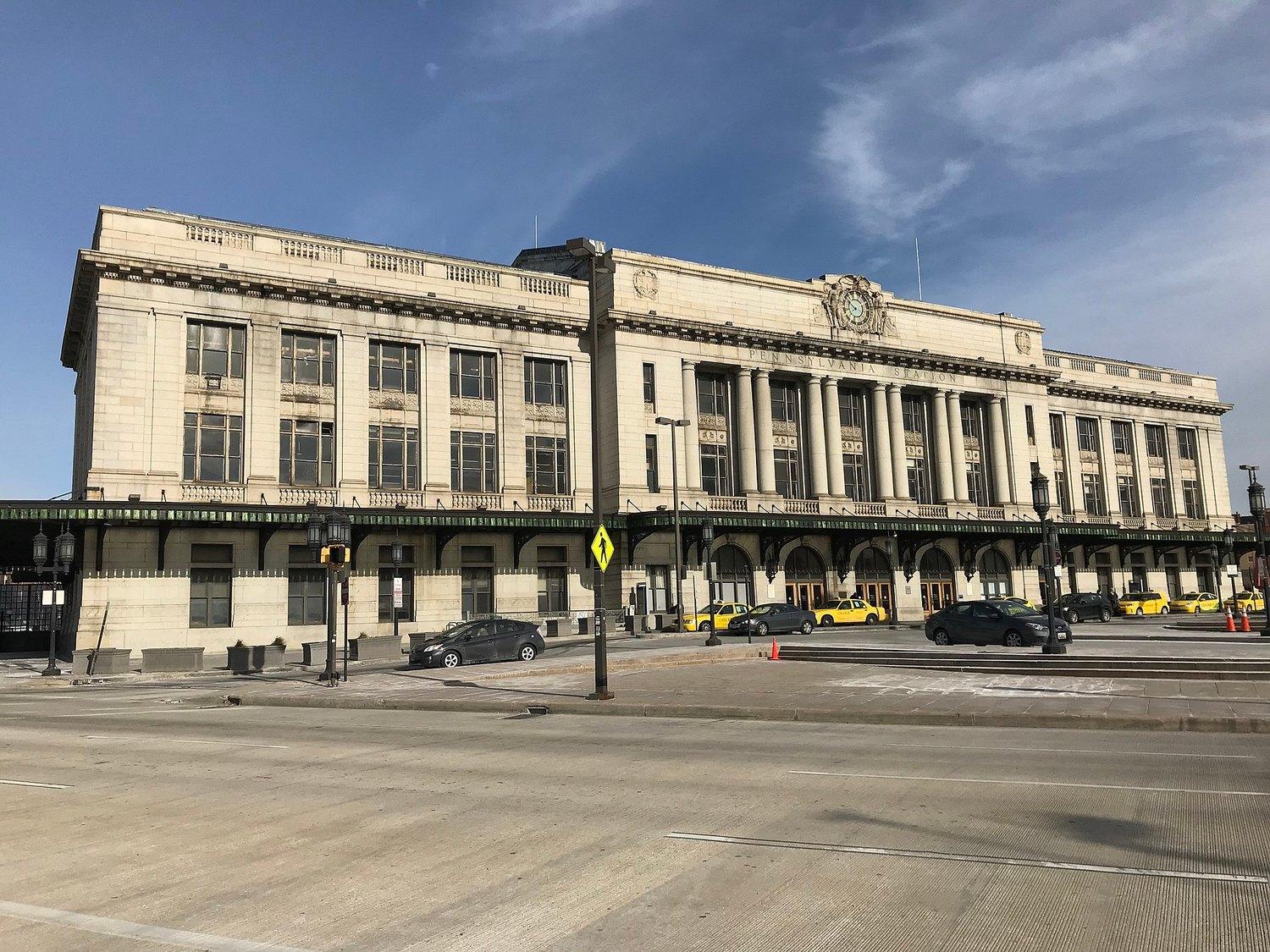 The Beaux-Arts front of Penn Station on Charles Street, its clock above the entrance and taxis at the kerb
