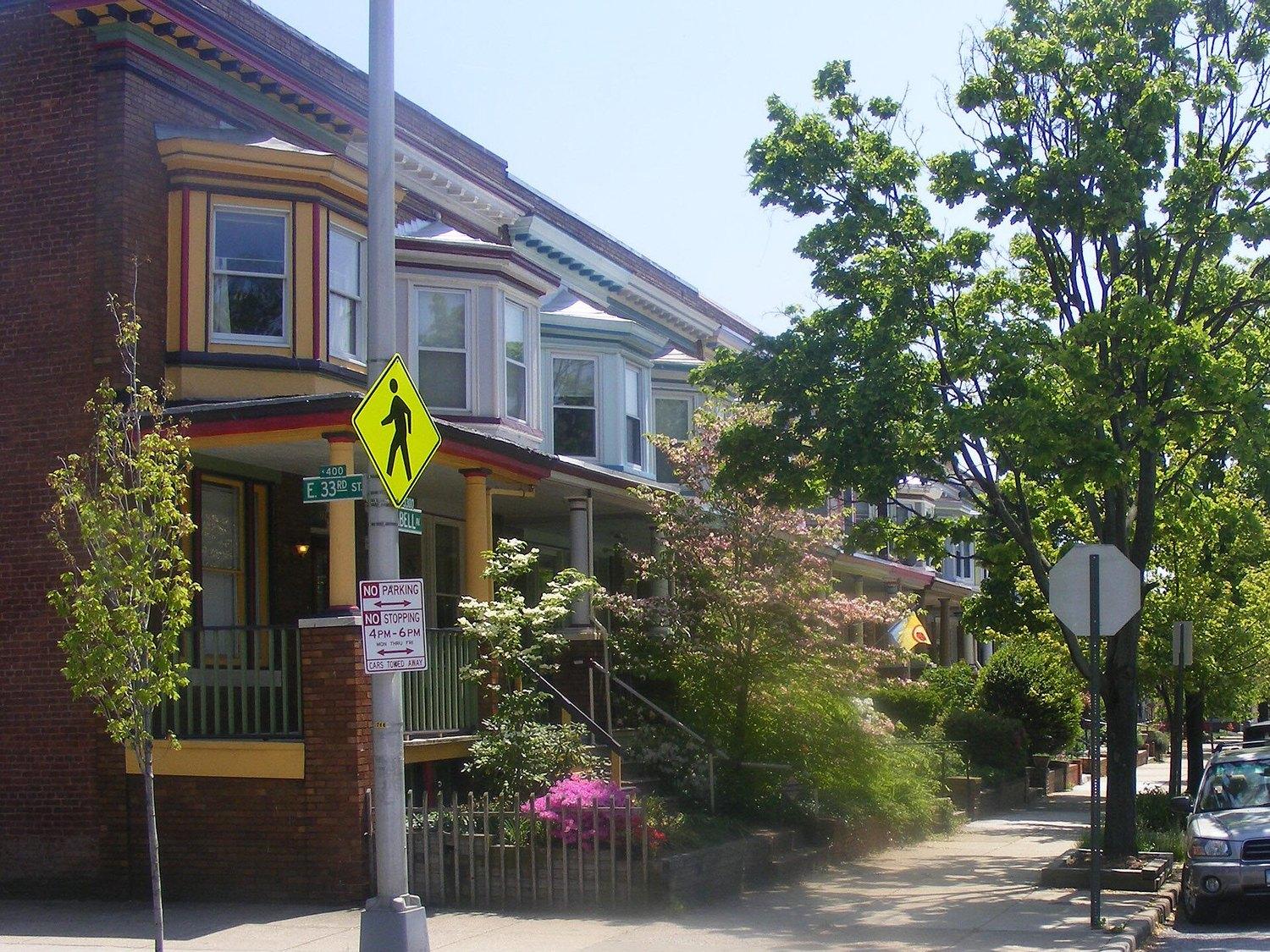 Charles Village rowhouses at 33rd and Abell, their cornices and porch posts painted in bands of yellow, red and green