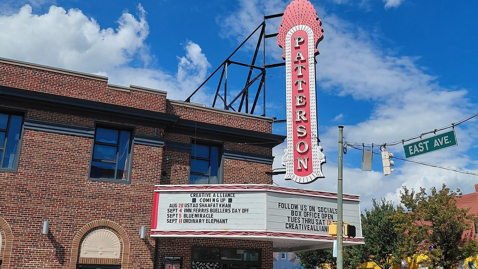 The Patterson's pink and white theatre sign and marquee over Eastern Avenue, the Creative Alliance's listings on the board
