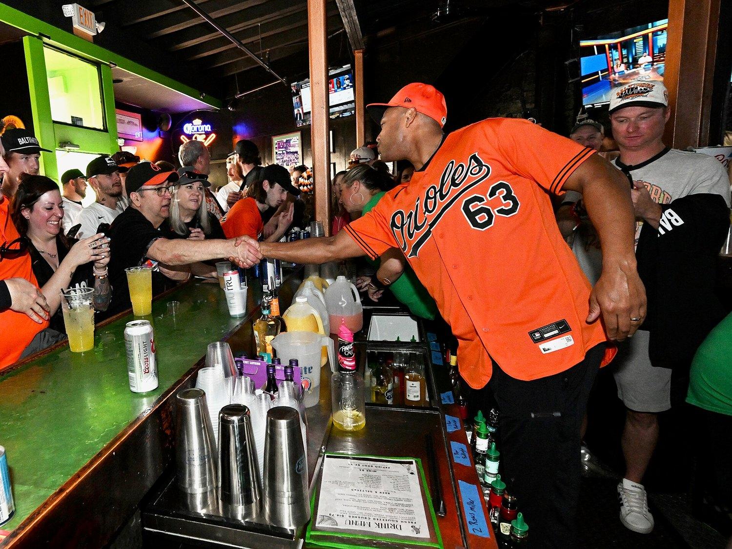 The bar at Pickles Pub packed on a game day, orange Orioles shirts three deep and a bartender in a number 63 jersey reaching across