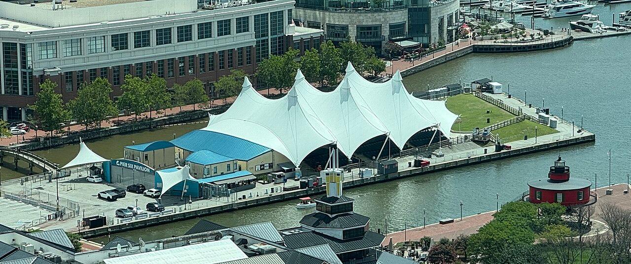 Pier Six Pavilion from above, its white peaked tent roof on the pier with the harbor and the Seven Foot Knoll lighthouse beside it