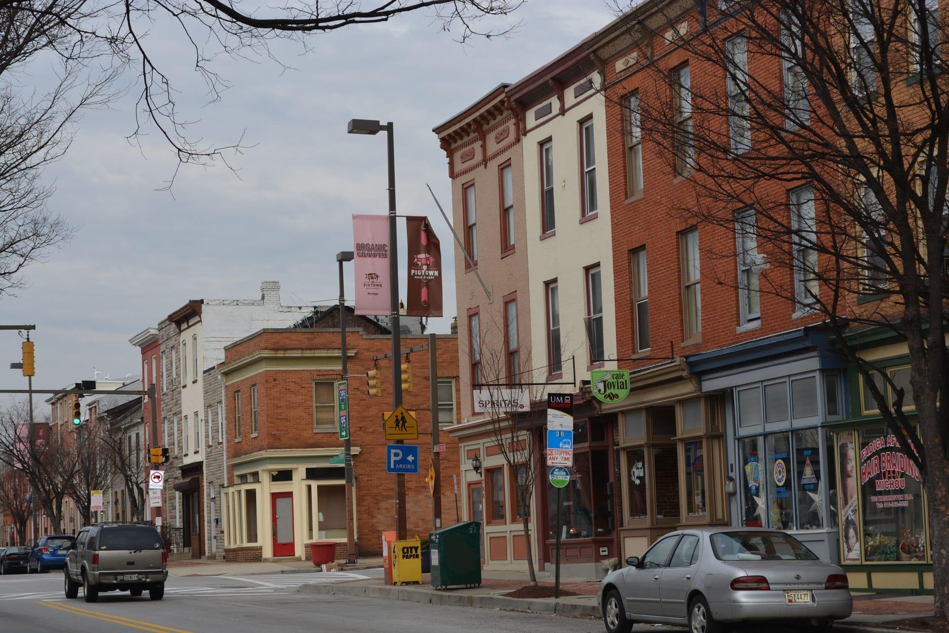 Washington Boulevard in Pigtown: Pigtown Main Street banners on a lamppost over brick shopfronts and rowhouses, photographed in 2015