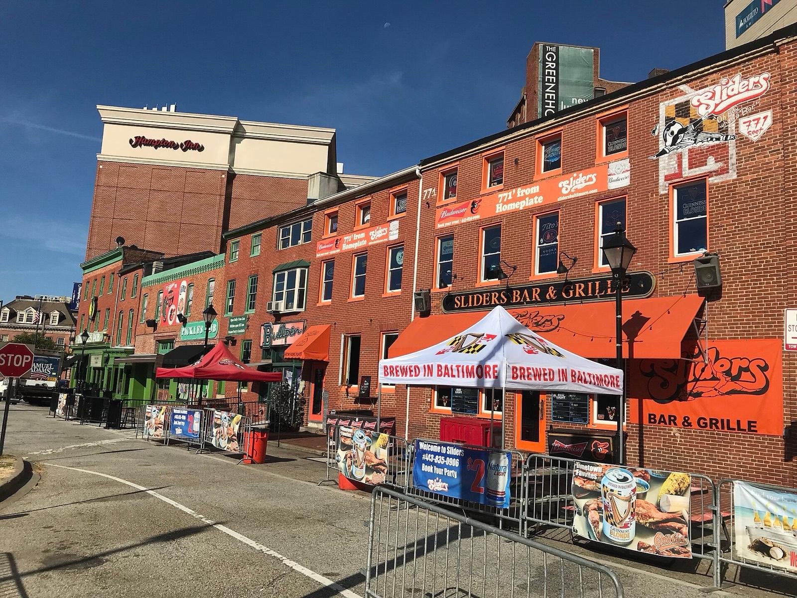 504 Washington Boulevard, the brick corner building Section 771 is in, photographed in 2019 when the bar there was Sliders, with orange awnings and a '771 feet from home plate' sign