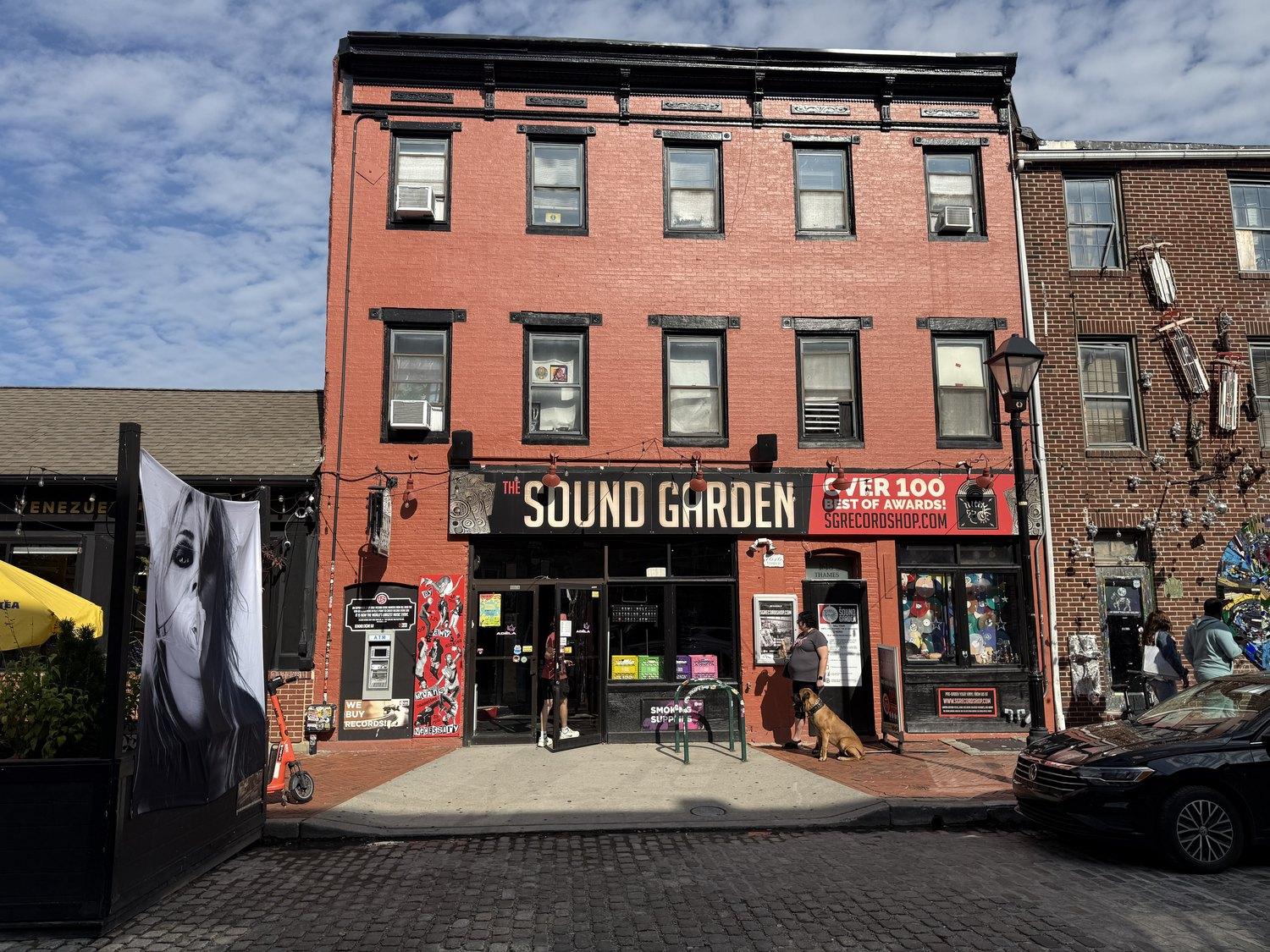 The Sound Garden's black awning on Thames Street, the shop open and a dog waiting outside