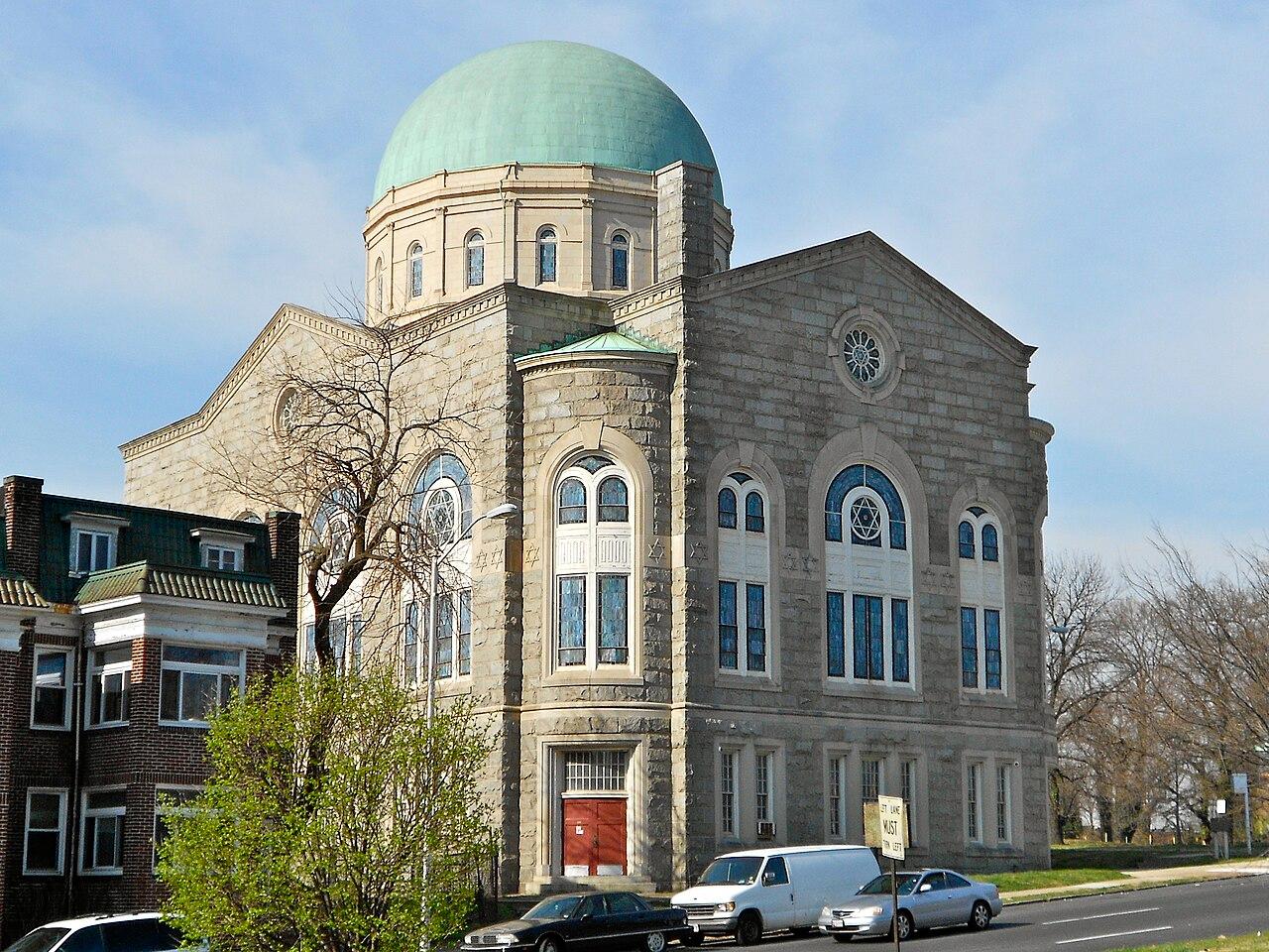 The Shaarei Tfiloh synagogue on Liberty Heights Avenue, a grey stone building with arched stained glass windows under a green copper dome, photographed in 2012