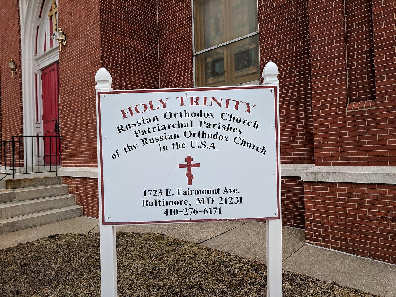The red brick front of Holy Trinity Russian Orthodox Church, 1723 E Fairmount Ave, with its red doors and the parish sign on the lawn